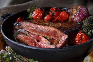 rustic food in the pan. food of animal origin. steak medium rare with Ganira of vegetables on a cast iron skillet. Food with a low-key picture.