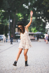 beautiful young woman in elegant hat and sunglasses posing outdoor