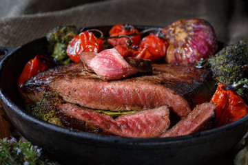Beef steak with vegetables on a cast-iron frying pan