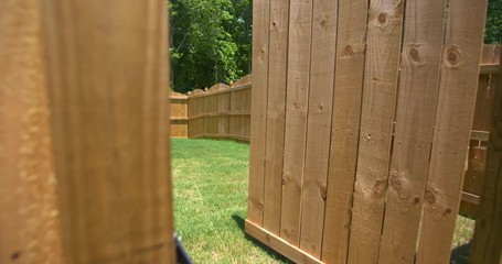 New Fence Gate Opens to Reveal Backyard. camera rises on a new fence as gate opens to reveal the rest of the new fenced enclosed backyard
