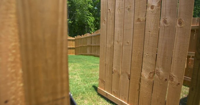 New Fence Gate Opens to Reveal Backyard. camera rises on a new fence as gate opens to reveal the rest of the new fenced enclosed backyard
