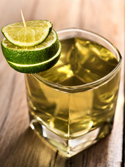 Alcohol drink. On wooden boards is glass with alcohol green transparent drink. A drink number three cocktail green tea with lime. Country life. Light background.