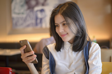 Attractive woman checking her messages on smartphone while sitti