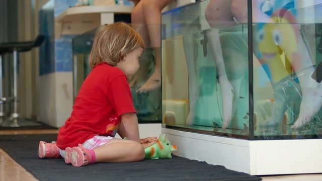 Cute baby playing in the fish-spa beauty saloon.