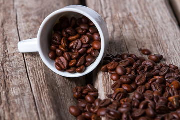Cup and roasted coffee beans. Coffee grains on wooden background. Ingredient of delicious drink. Cup on old shelf.