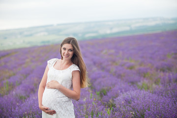 Fototapeta na wymiar Lavender field and a happy pregnant woman