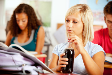 Students: Girl Opening Bottle Of Soda In Class
