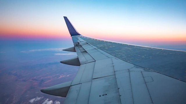 Plane Wing Aerial View During Sunset. view outside a plane window of the wing during sunset high above the surface
