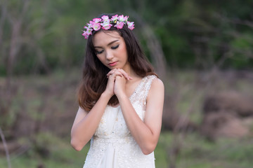 beautiful young woman in white dress with flower on her hair hol
