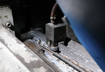 Action shot of speeding industrial bandsaw blade with coolant, showing motion blur