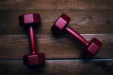 Two red dumbbells on a wooden background