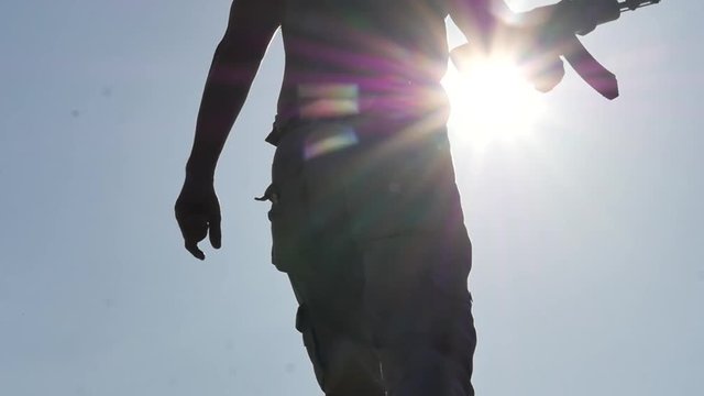 moving up man with Kalashnikov assault rifle silhouette raises his hand slow motion