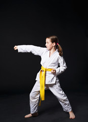 Child girl in karate suit with yellow belt show stance