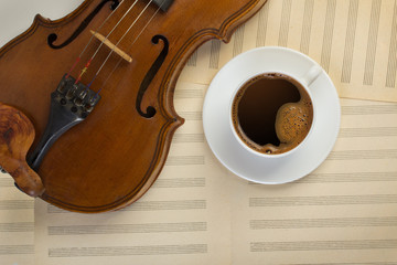 Fototapeta premium old violin and white coffee cup on musical sheets
