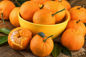 Tangerines in yellow bowl. Fresh tangerines on rustic background.