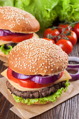 Homemade cheeseburger on brown wooden surface.