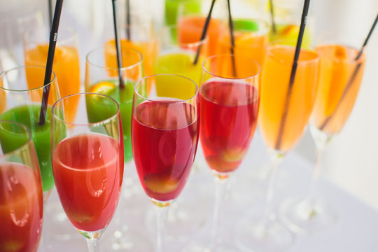 Beautiful line of different colored cocktails with smoke on a party, tequila, martini, vodka, and others on decorated catering bouquet table on open air party
