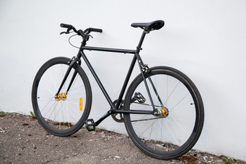 Obraz na płótnie Canvas Black fixed-gear bicycle standing near gray wall