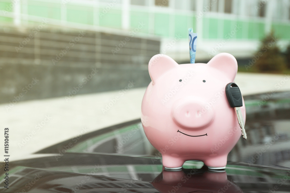 Poster Piggy money box with cash and key on car bonnet at the street