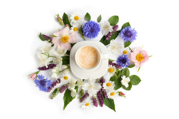Cup of coffee with fresh flowers lying around on white background