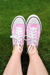 Woman feet in youth sneakers on green grass