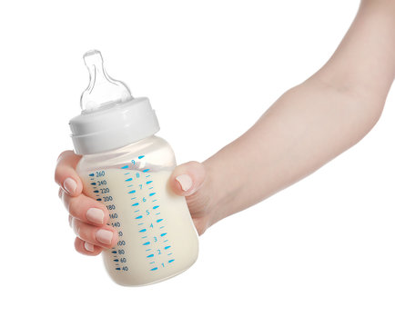 Female hand holding a baby bottle of milk on white background