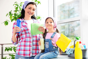 Daughter and mother with cleaning set in kitchen