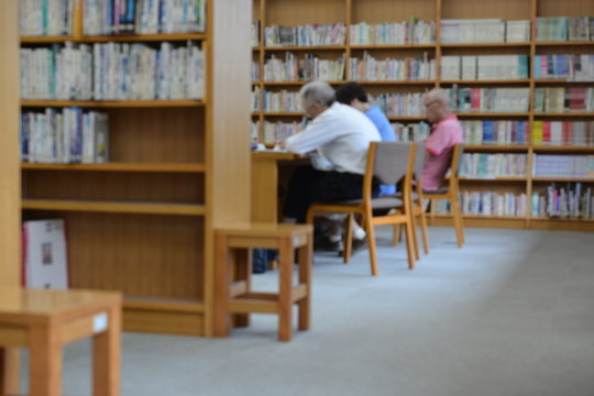 図書館の机で本を読んでる人