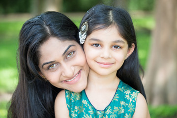 Closeup portrait, mom enjoying time with daughter, isolated outside green trees background