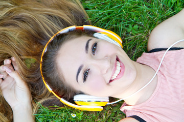Girl listening to music streaming with headphones in summer on a