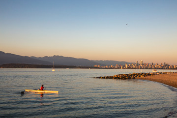 Rower paddling back to shore at Jericho Beach, with Vancouver Downtown in the Background.