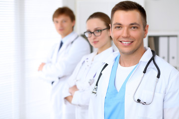 Fototapeta premium Cheerful smiling male doctor with medical staff at the hospital