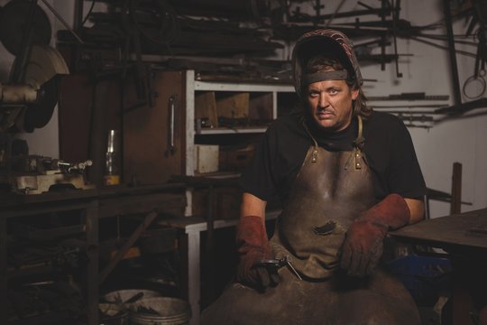Portrait of blacksmith sitting in workshop