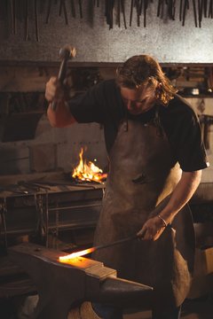Blacksmith working on hot metal using hammer to shape