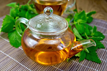 Tea with mint in glass teapot on wooden board