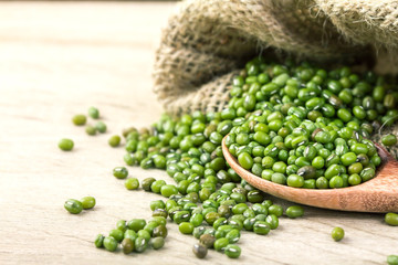 close up green mung beans in wooden spoon on wood plate