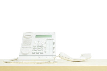 Closeup white phone , office phone on blurred wooden desk in the meeting room under window light isolated on white background