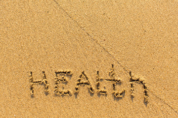 Health - drawn by hand on a sandy golden sea beach.