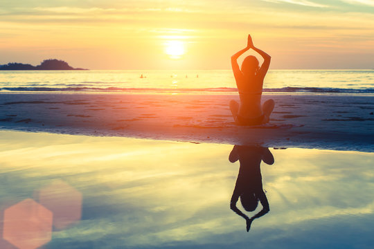 Silhouette meditation yoga woman on background of sunset sea.