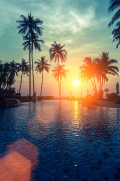 Tropical sunset and silhouettes of palm trees on sea beach.