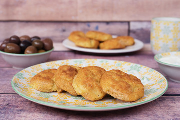 Baked potato meatballs balls in a yellow plate. Back olives and yogurt sauce. Closeup, fresh tones. wood background