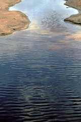 Water surface with ripples and sunrays reflections