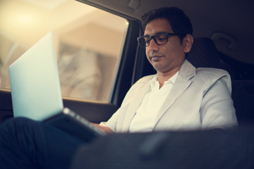 indian business male using laptop inside the car