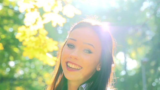 Slowmotion young beautiful happy girl stands in woods with sunshine above her head