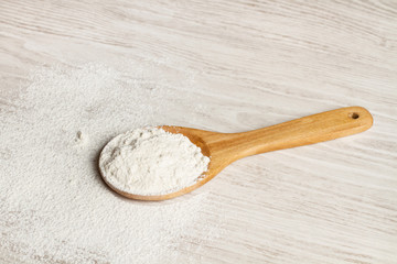 Cuchara de madera con harina sobre una tabla blanca rústica. Vista superior. Copy space