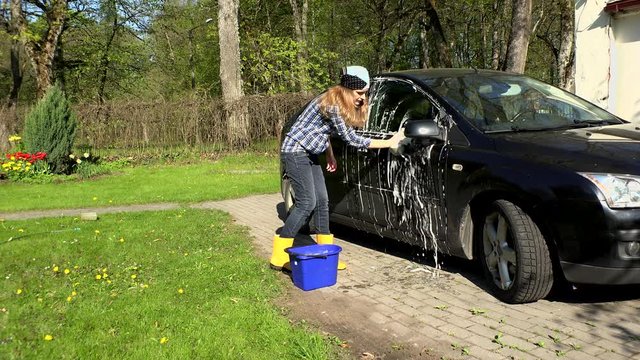 woman wash black car with soapy sponge.