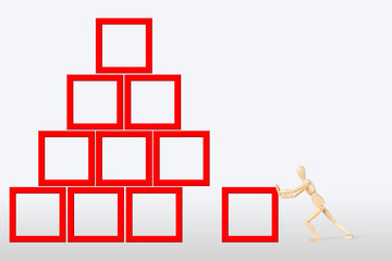 Man builds a construction as a pyramid. Abstract image with a wooden puppet
