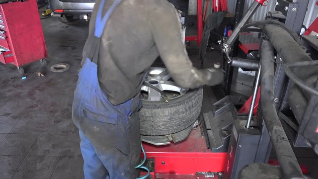 mechanic inflating tire on wheel in workshop