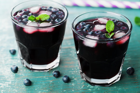 Blueberry lemonade or cocktail on teal rustic table, summer berry juice