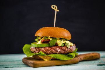 Tasty grilled tuna burger with lettuce and mayonnaise served on wooden table
